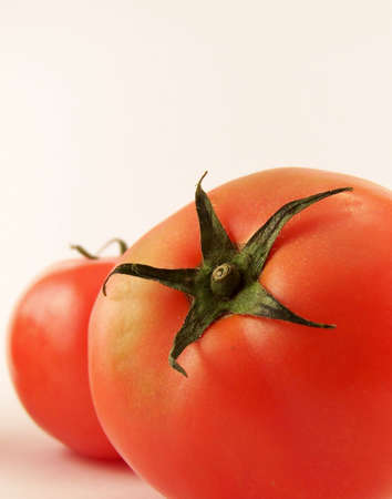Image of red tomatoes, with focus on star-shaped stem.  Vertical orientation.の写真素材