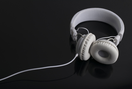 Isolated modern white headphone on a black reflected background.の写真素材