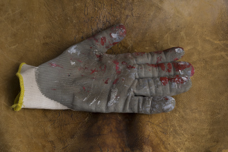 worn worker's gloves in a brown leather background.