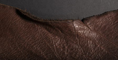 Isolated vintage weathered old brown leather on a dark backgroundの写真素材
