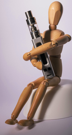Isolated vaping electronic cigarette hold by a wooden figure.の写真素材