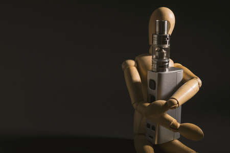 wooden dummy isolated and holding and electronic cigarette, e cig, for vaping devices.の写真素材
