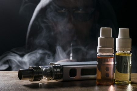 isolated vaping e liquid and vaping device for electronic cigarette on a dark background.の写真素材