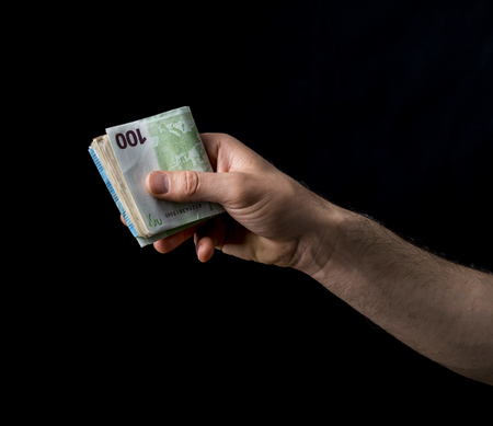 holding 100 euro money, hand holding one hundred euro cash isolated on a black background