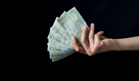 holding 100 euro money, hand holding one hundred euro cash isolated on a black backgroundの写真素材