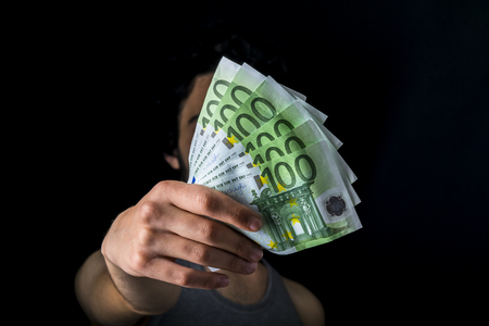 holding 100 euro money, hand holding one hundred euro cash isolated on a black backgroundの写真素材