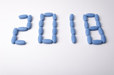 Creative 2018 new year concept made out blue medical tablets over a white background.の写真素材