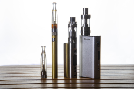 Popular vaping e cig devices mod and pen.electronic cigarette over a wood background. vaporizer e-cig old device model over a white background.の写真素材