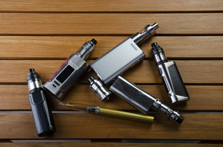Popular vaping e cig devices mod.electronic cigarette over a wood background. vaporizer e-cig old device model.の写真素材
