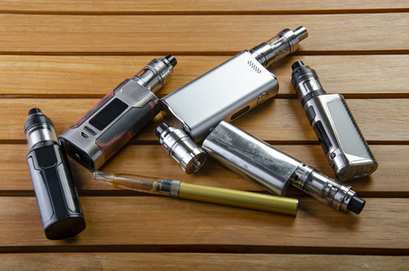 Popular vaping e cig devices mod.electronic cigarette over a wood background. vaporizer e-cig old device model.の写真素材