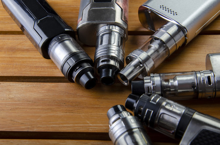 Popular vaping e cig devices mod.electronic cigarette over a wood background. vaporizer e-cig old device model.の写真素材