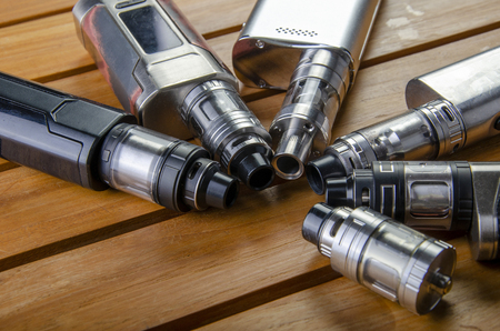 Popular vaping e cig devices mod.electronic cigarette over a wood background. vaporizer e-cig old device model.の写真素材