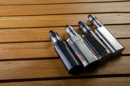 Popular vaping e cig devices mod.electronic cigarette over a wood background. vaporizer e-cig old device model.の写真素材