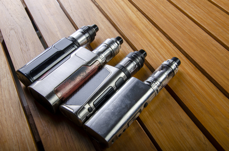 Popular vaping e cig devices mod.electronic cigarette over a wood background. vaporizer e-cig old device model.の写真素材
