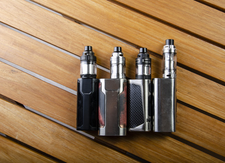 Popular vaping e cig devices mod.electronic cigarette over a wood background. vaporizer e-cig old device model.の写真素材