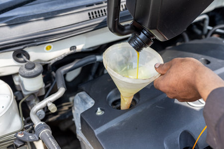 Pouring motor oil to engine with the help of a funnelの写真素材