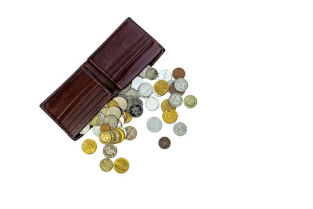 A brown leather wallet with coins spreading out from it on isolated white background top view. selective focusの写真素材