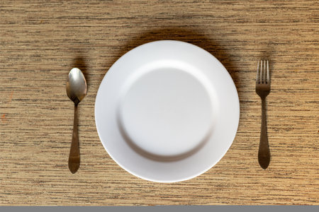 Dinner plate with spoon and fork on a table flat lay top viewの写真素材