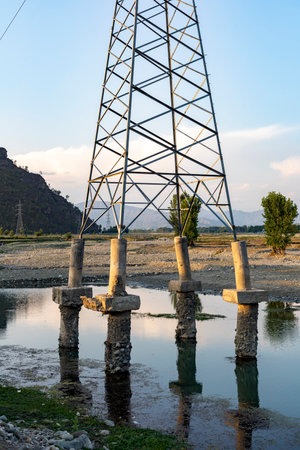 High voltage post in the river water after a heavy flood in the area erode the soil form the pillarsの写真素材