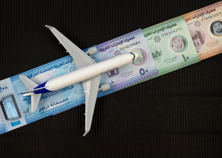 A runway made of UAE currency notes. Toy airplane on the runway of United Arab Emirates banknotes. Travel or tourism concept.の写真素材
