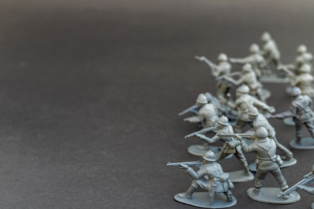 Group of gray toy soldiers in battle stance on dark backgroundの写真素材