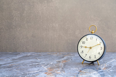 Classic table clock on a marble floor with space for your text.の写真素材