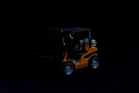 Yellow toy forklift vehicle on black backgroundの写真素材