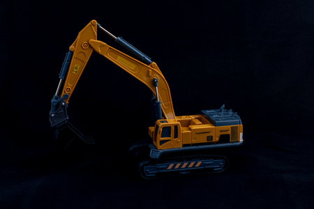 Toy excavator or digger on black background. Heavy construction vehicle concept.の写真素材