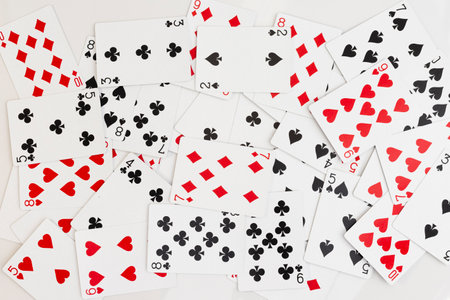Scattered playing cards with mixed suits and numbers on white backgroundの写真素材