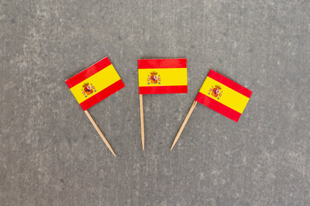 Three Miniature Spanish Flags Arranged on Gray Backgroundの写真素材