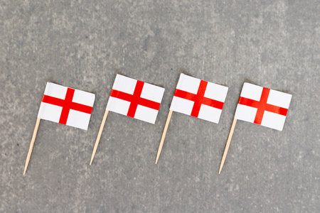 Row of Four Small England Flags on Wooden Sticks Lined Up on Gray Backgroundの写真素材