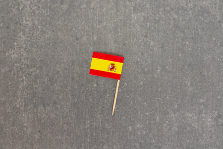 Mini Spanish Flag on Toothpick Against Gray Backgroundの写真素材