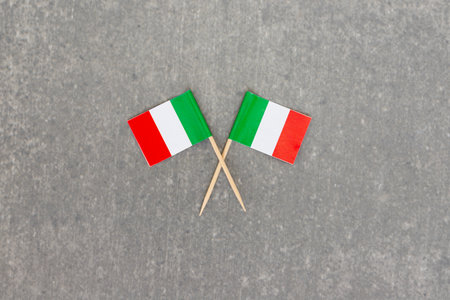 Two Mini Italian Flags Crossed on Gray Stone Backgroundの写真素材