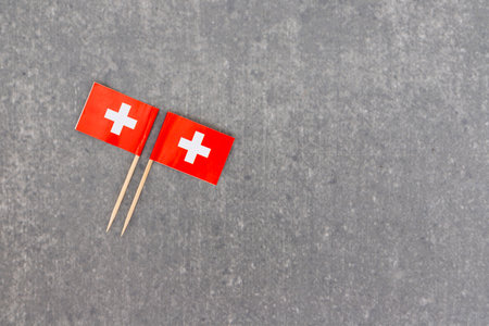 Two Swiss Flags Aligned Left on Gray Background with Blank Space for Textの写真素材