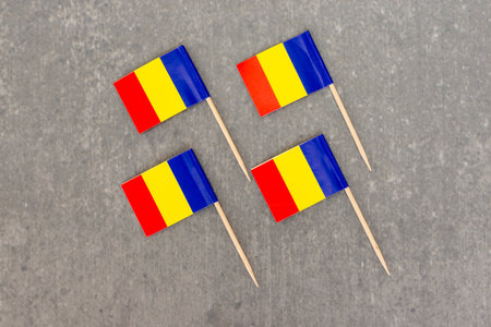 Four Romanian Flag Toothpicks Displayed on Concrete Surfaceの写真素材