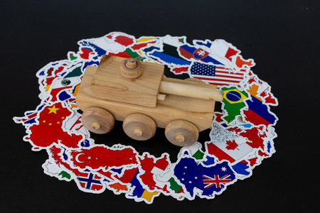 Wooden Toy Tank Over International Flags Symbolizing Global Military Conceptの写真素材