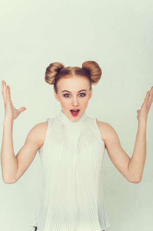Portrait of surprised beautiful girl with funny hairstyle with open hand and open-mouthed.