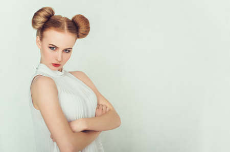 Close-up portrait of offended beautiful girl with funny hairstyle looking at camera.の写真素材