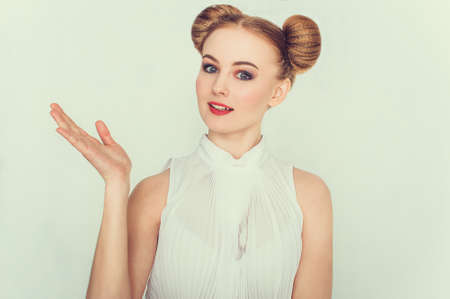 Close-up portrait of smilling beautiful girl with funny hairstyle with open hand and open-mouthed.