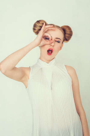 Beautiful girl with funny hairstyle. Smiling young woman making ok hand gesture