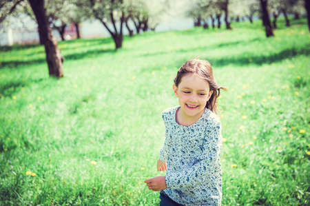 Happy little girl running in the garden. Child in spring fruit orchard.の写真素材