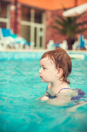 Happy child in swimming pool, beautiful girl swimsの写真素材