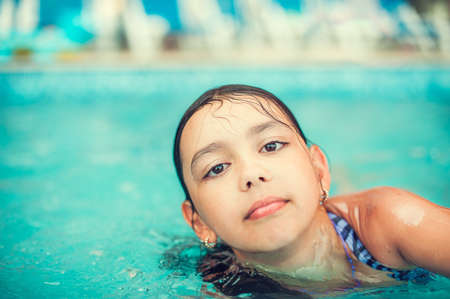 Happy child in swimming pool, beautiful girl swimsの写真素材