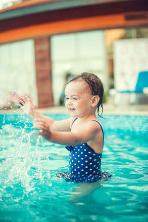 Little happy girl in swimming pool. Kid splashing on poolの写真素材