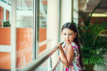 Beautiful little girl in dress standing in a hotelの写真素材