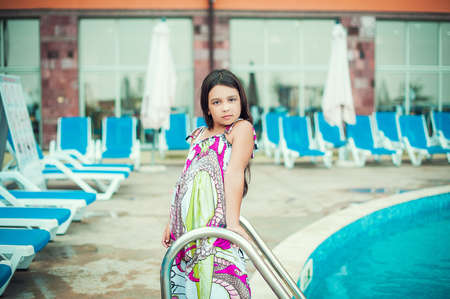 Beautiful girl standing near swimming pool, looking at camera.の写真素材