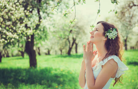 Close-up portrait beautiful girl with a flower in her hair in the apple orchardの写真素材