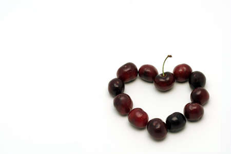 Heart made with deep red cherries, isolated on whiteの写真素材