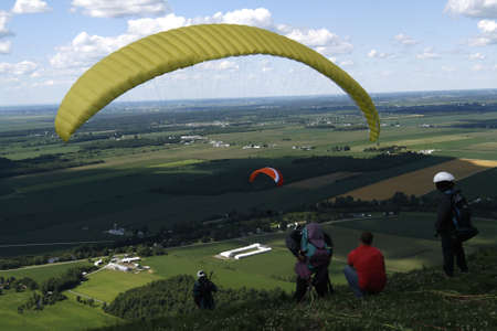 Paraglider ready to jump. Two others waiting with their instructorの写真素材
