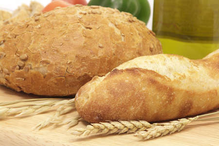 Breads on wood with wheat ears and oat, on a mediterranean background